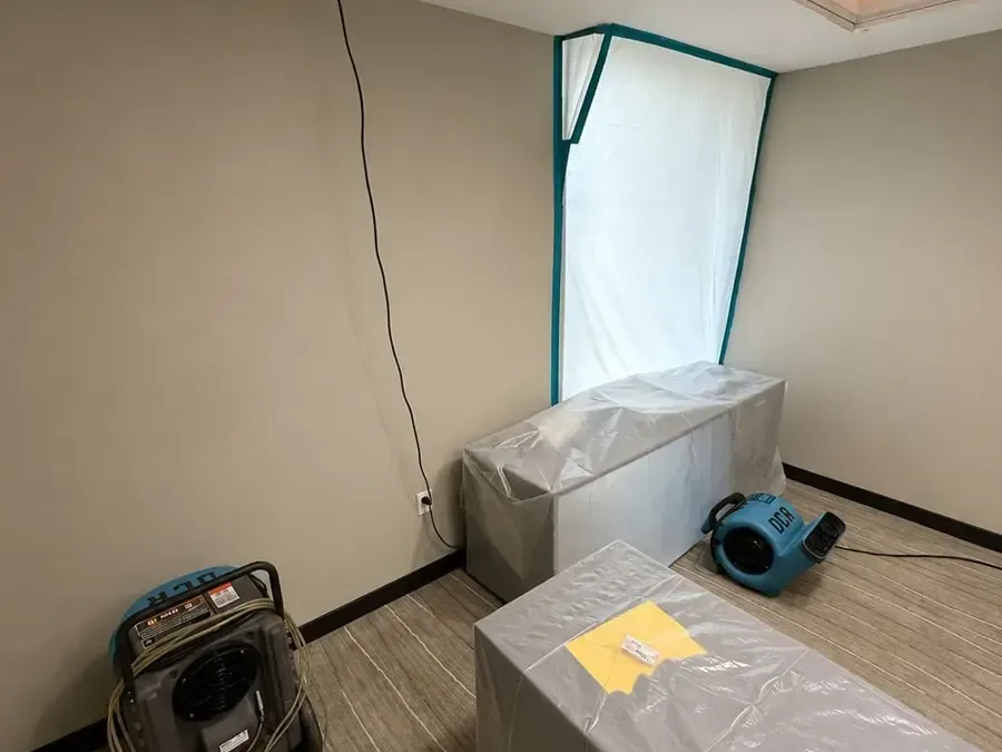 Plastic containment and air movers in a room prepared for structural drying