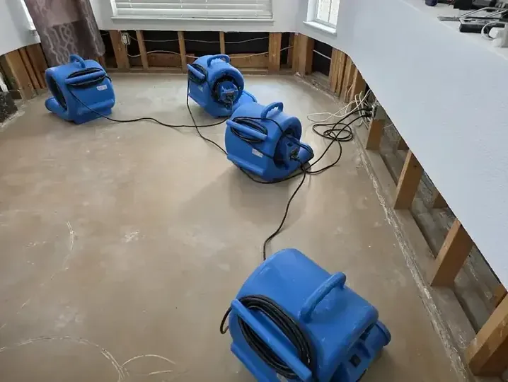 Blue air movers arranged across a bare floor beside opened lower walls
