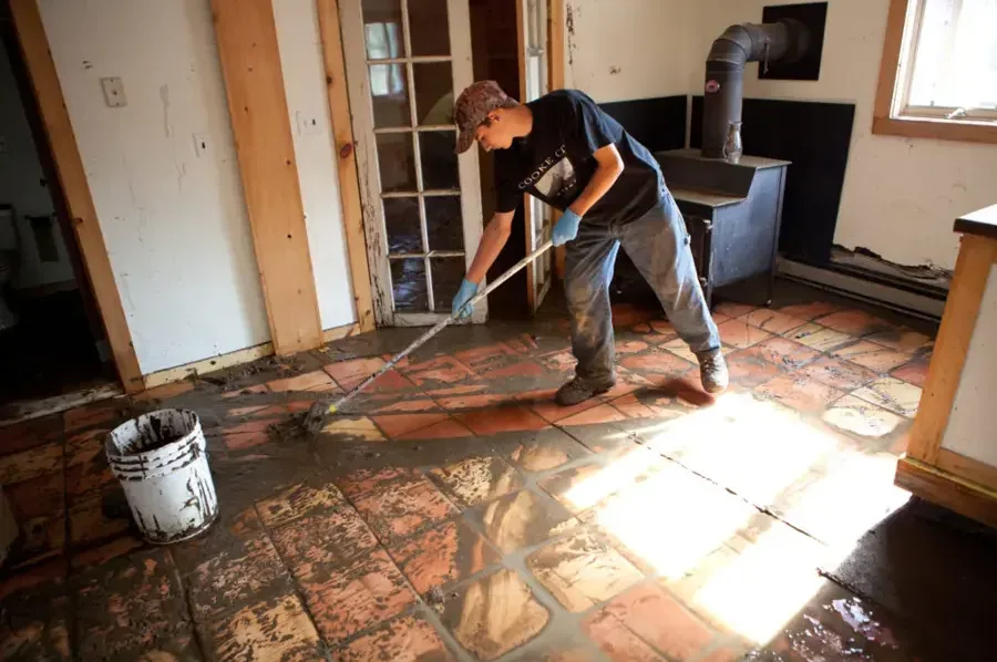 Mud and runoff being removed from a tile floor after floodwater entered a room
