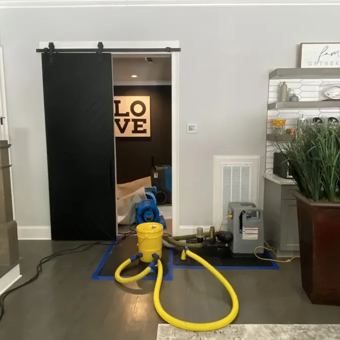 Yellow drying hoses and portable equipment beside an open interior doorway